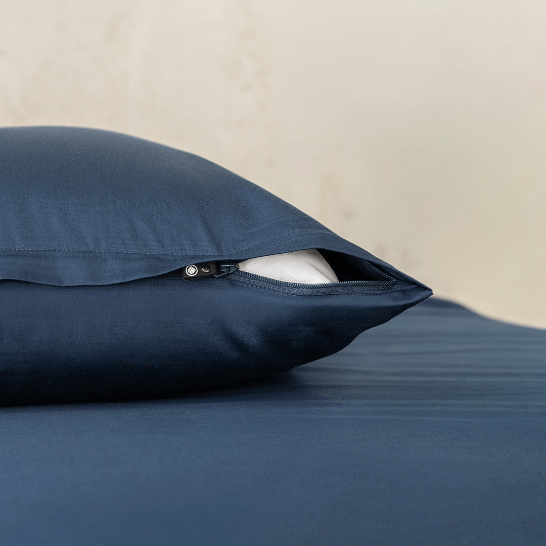 Close-up of a navy blue pillowcase showing a partially open zipper closure revealing white pillow fill