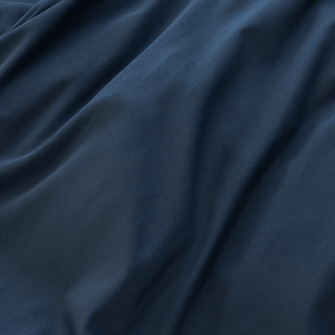 Extreme close-up showing the soft folds and smooth texture of navy blue cotton fabric