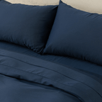 Close-up view of navy blue pillowcases resting above a matching flat sheet and quilt cover