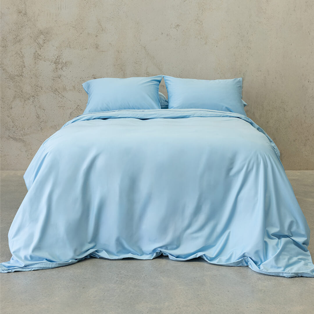 Pastel blue quilt cover set on a bed, with a neutral background. 