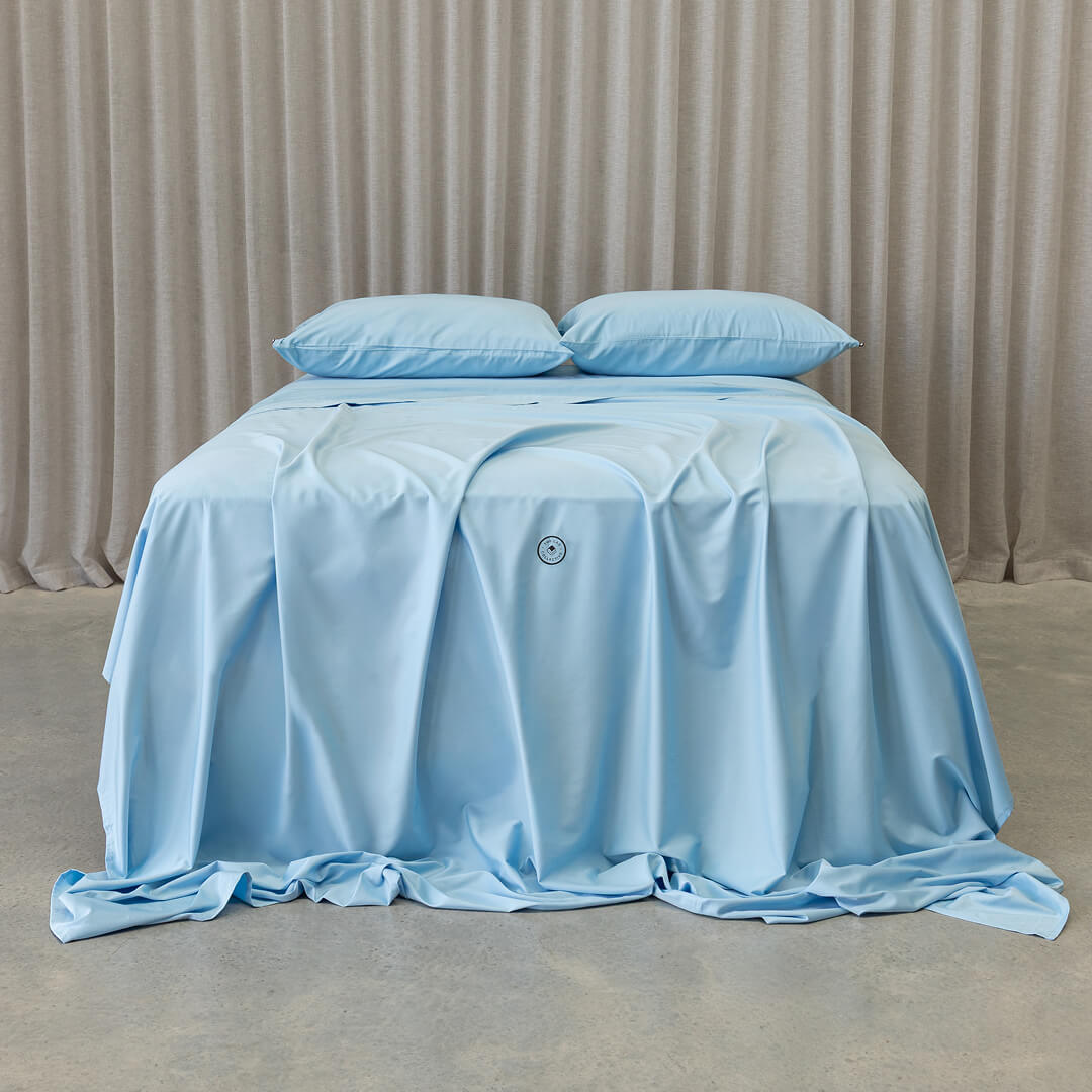 Pastel blue bedding set on a bed with a neutral background.
