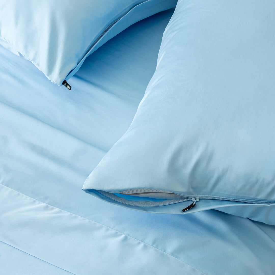 Pastel blue pillowcases on a bed, showcasing their invisible zips.
