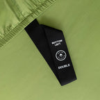 Close-up of a green fabric with a black label on a matching green background.