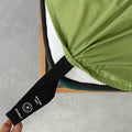 Labelled corner loop strap on a green fitted sheet being pulled by a hand onto the mattress.