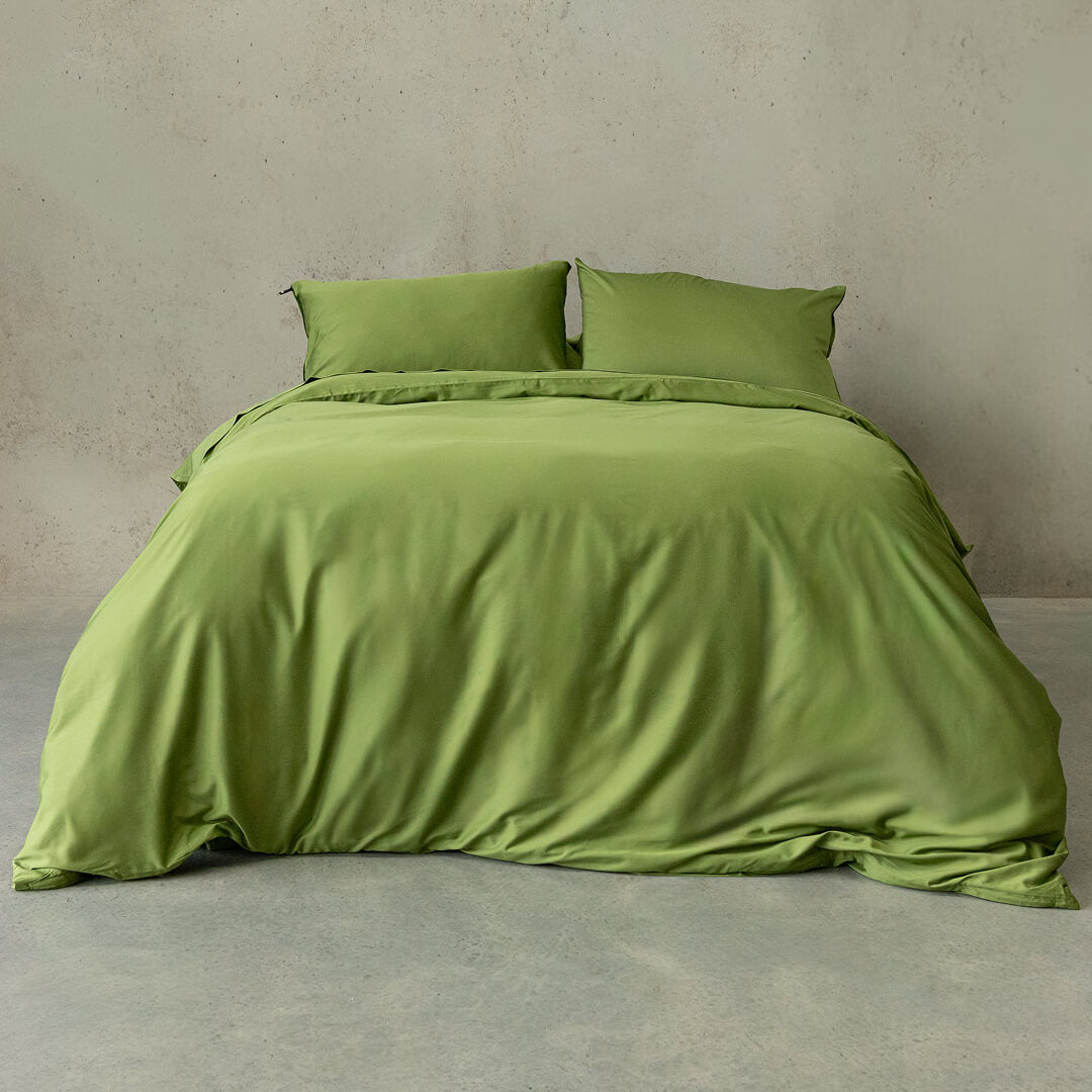 Green bedding set on a bed against a plain wall.
