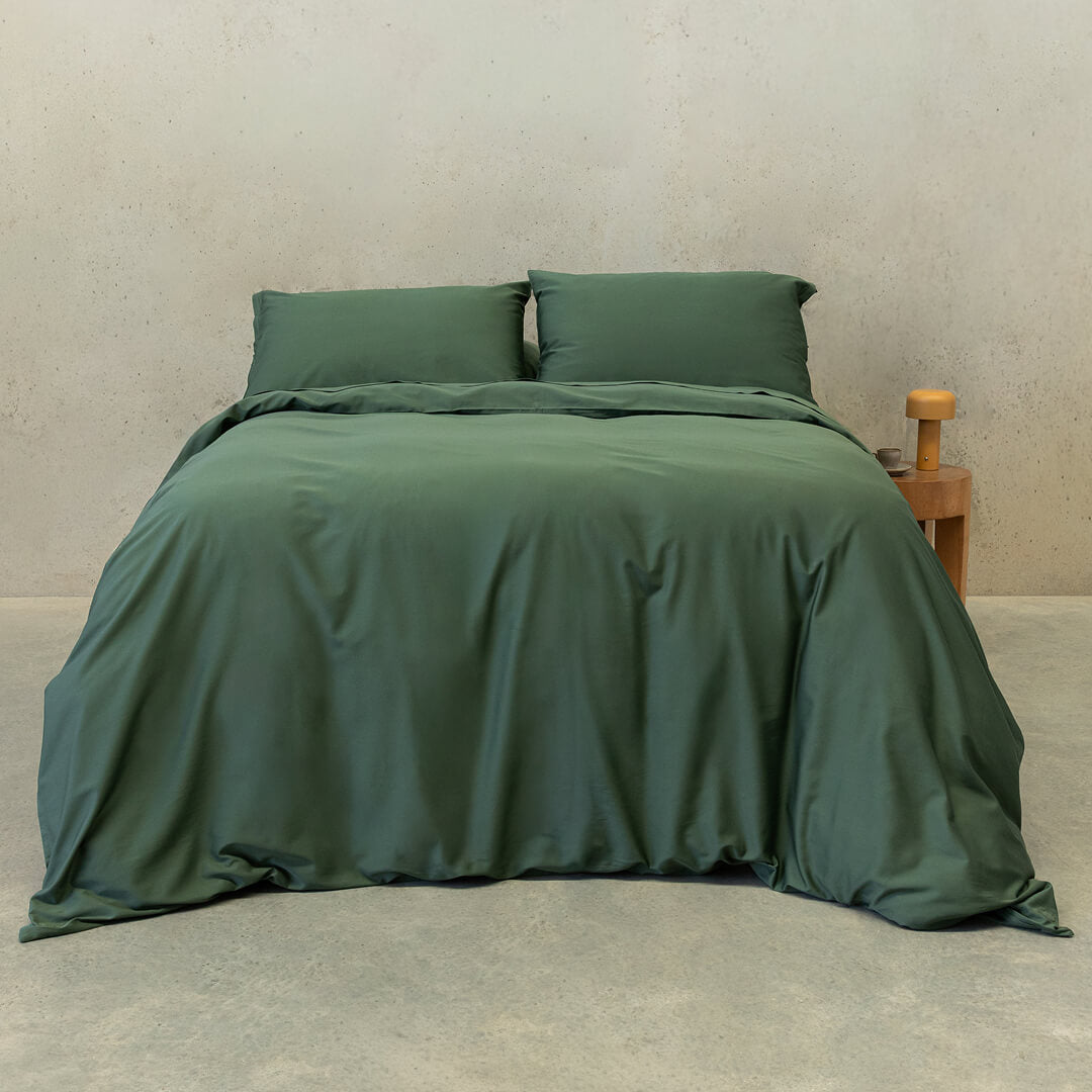 Dark green quilt cover set on a bed.