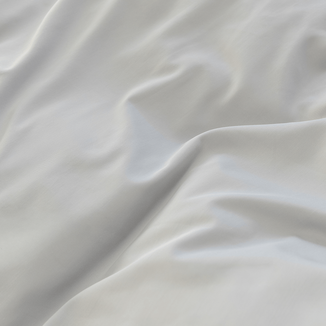 Detailed close-up of smooth gray quilt cover fabric arranged in soft folds and gentle waves.
