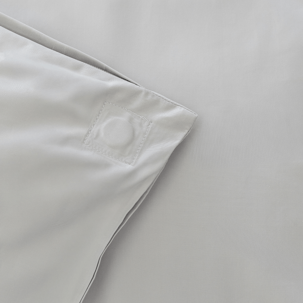 Close-up of the corner of a gray quilt cover showing a stitched square detail and clean finished seams.