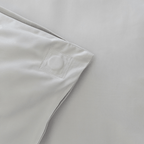 Close-up of the corner of a gray quilt cover showing a stitched square detail and clean finished seams.