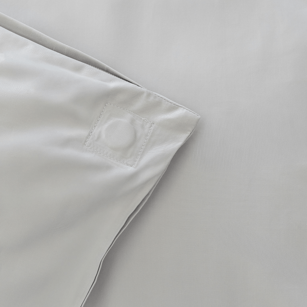 Close-up of the corner of a gray quilt cover showing a stitched square detail and clean finished seams.