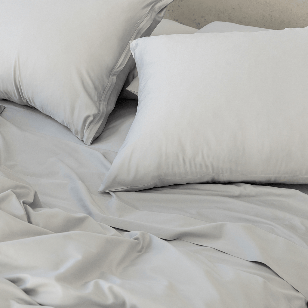Close-up of gray pillows arranged on matching gray bedding, highlighting the smooth fabric and soft finish.