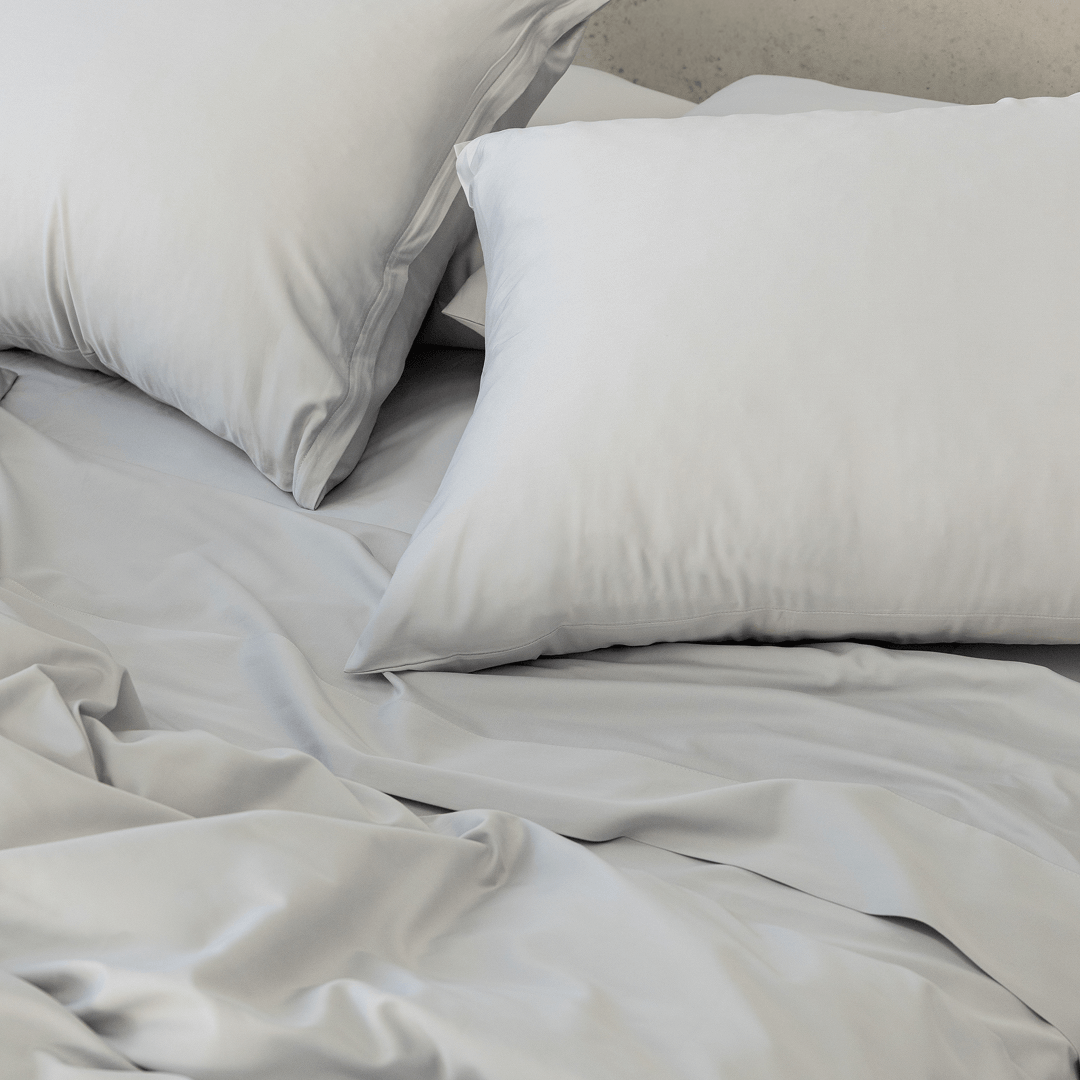 Close-up of gray pillows arranged on matching gray bedding, highlighting the smooth fabric and soft finish.