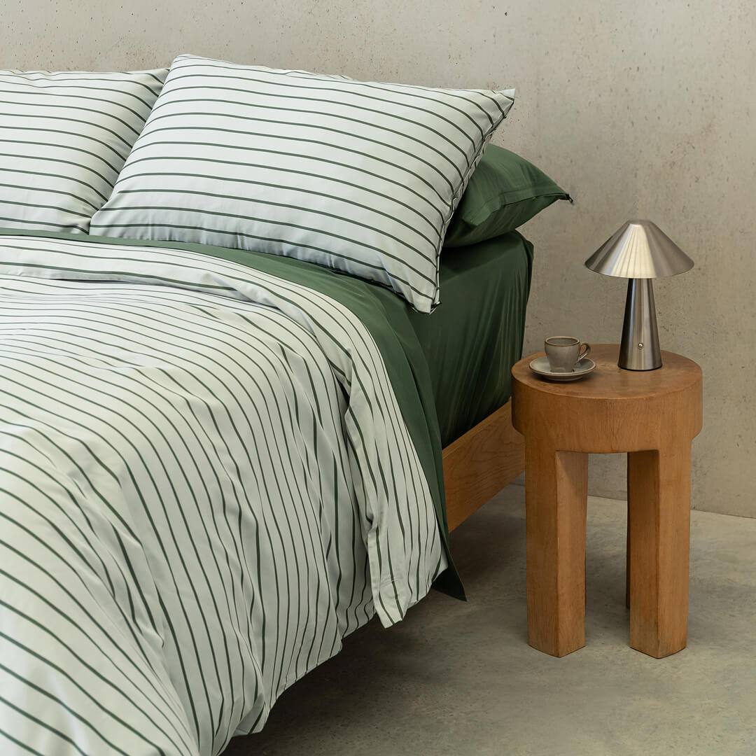 Stripe quilt cover paired with green sheets on bed.