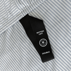 Close-up of a black fitted-sheet corner strap labelled “Bottom Left” and “Double” against gray and white striped fabric.