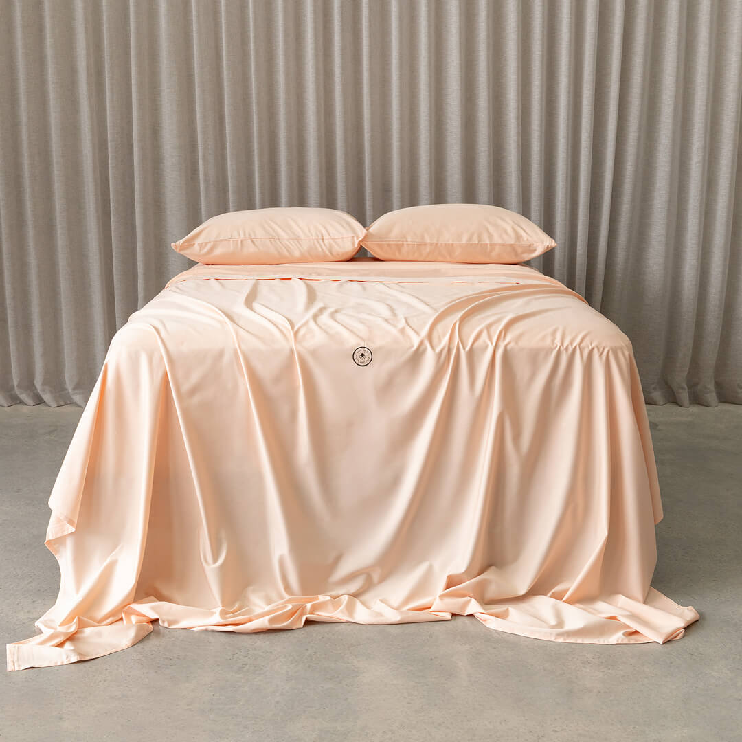 Peach bedspread on a bed with a neutral background.