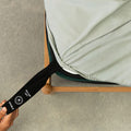 Light grey fitted sheet with labelled corner strap being pulled.
