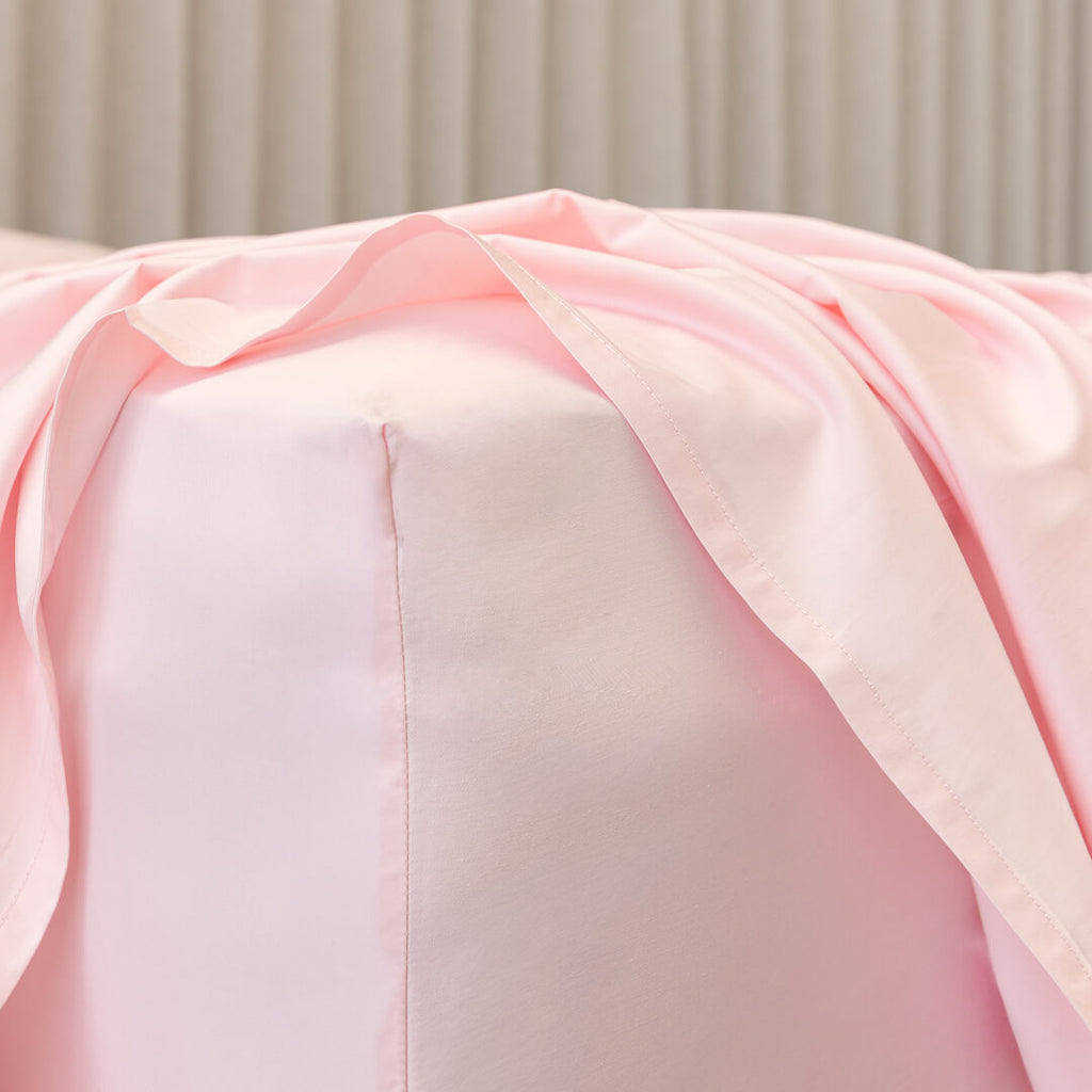 Close-up of a pink fitted sheet corner fabric on bed.