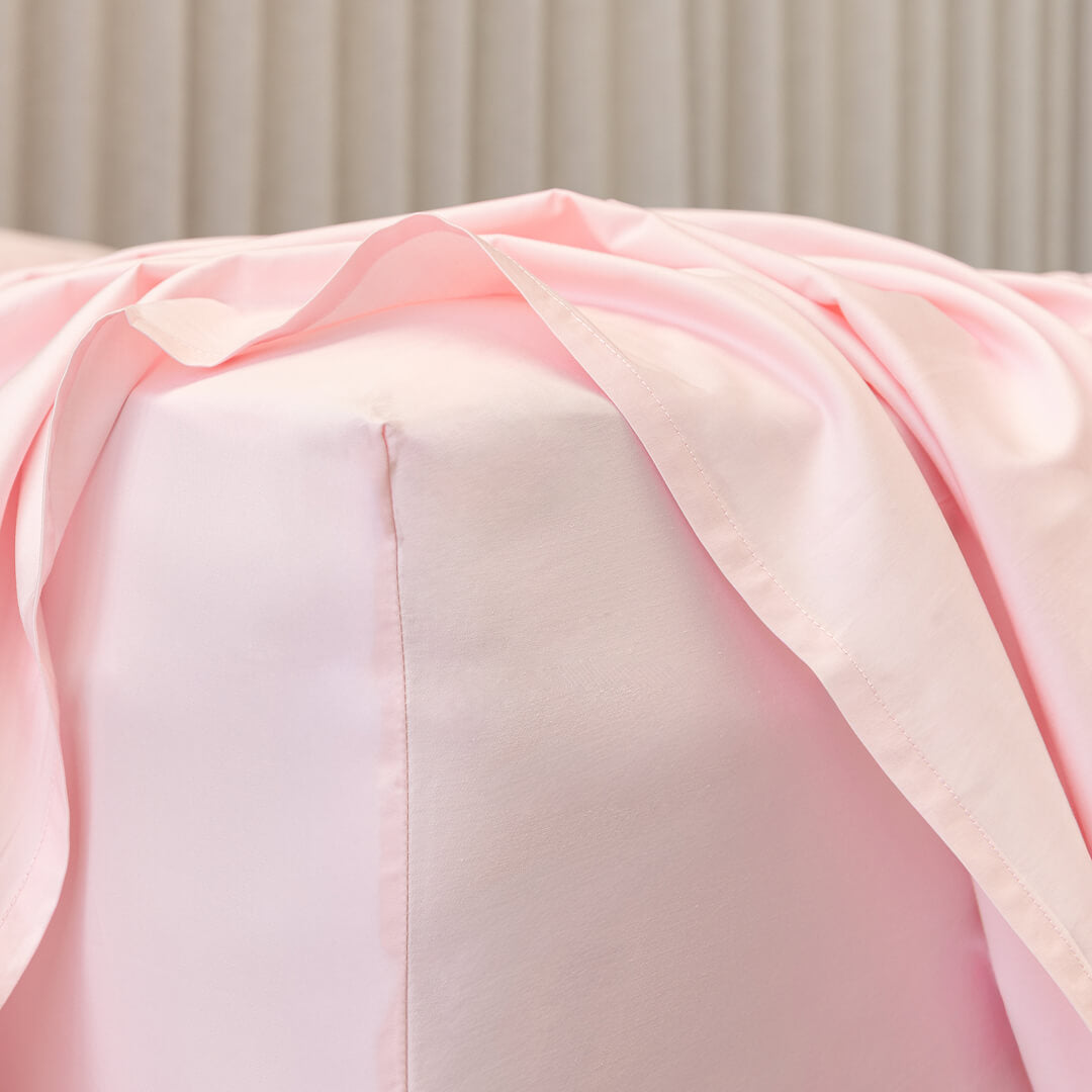 Close-up of a pink fitted sheet corner fabric on bed.