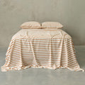 Striped bedspread on a bed against a plain wall.