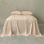 Striped bedspread on a bed against a plain wall.