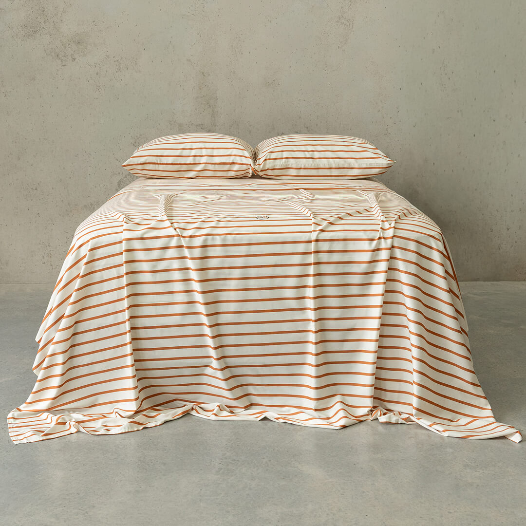 Striped bedspread on a bed against a plain wall.