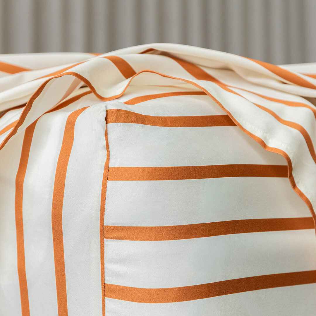Close-up of a striped fabric with orange and white stripes on a neutral background.