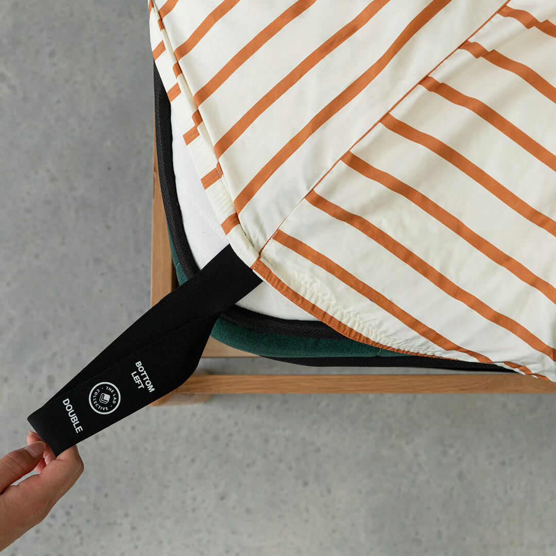 Striped fitted sheet with a black strap labeled 'Double' on a grey background.