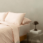 Close-up of blush pink quilt cover and pillowcases on a neatly styled bed, highlighting the smooth fabric, soft texture, and premium finish.
