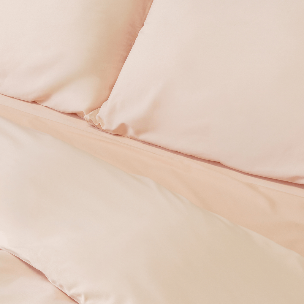 Close-up of matching blush pink pillowcases and quilt cover, highlighting the silky-smooth texture, clean lines, and coordinated bedding design.