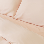 Close-up of matching blush pink pillowcases and quilt cover, highlighting the silky-smooth texture, clean lines, and coordinated bedding design.