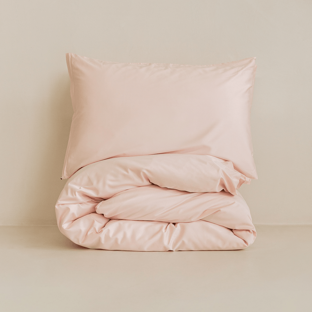 Folded blush pink quilt cover set with matching pillowcase, highlighting the soft fabric, premium finish, and minimalist presentation.