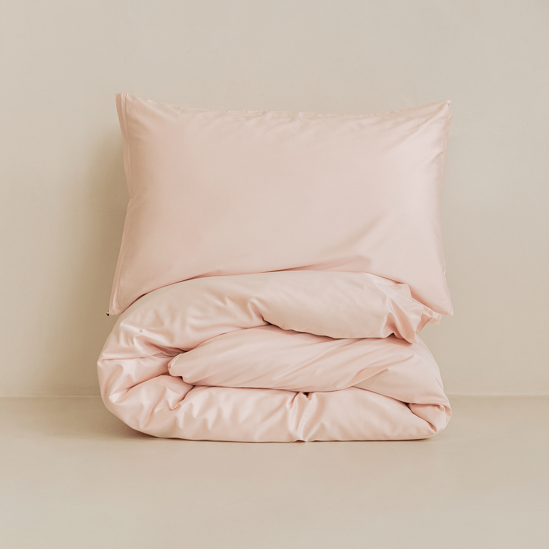 Folded blush pink quilt cover set with matching pillowcase, highlighting the soft fabric, premium finish, and minimalist presentation.