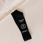 Close-up of a fitted sheet orientation tag labeled “Bottom Left,” designed to simplify bed-making and help identify the correct sheet position.