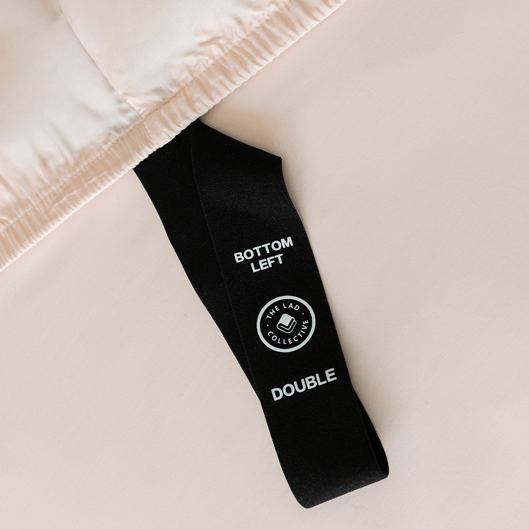 Close-up of a fitted sheet orientation tag labeled “Bottom Left,” designed to simplify bed-making and help identify the correct sheet position.
