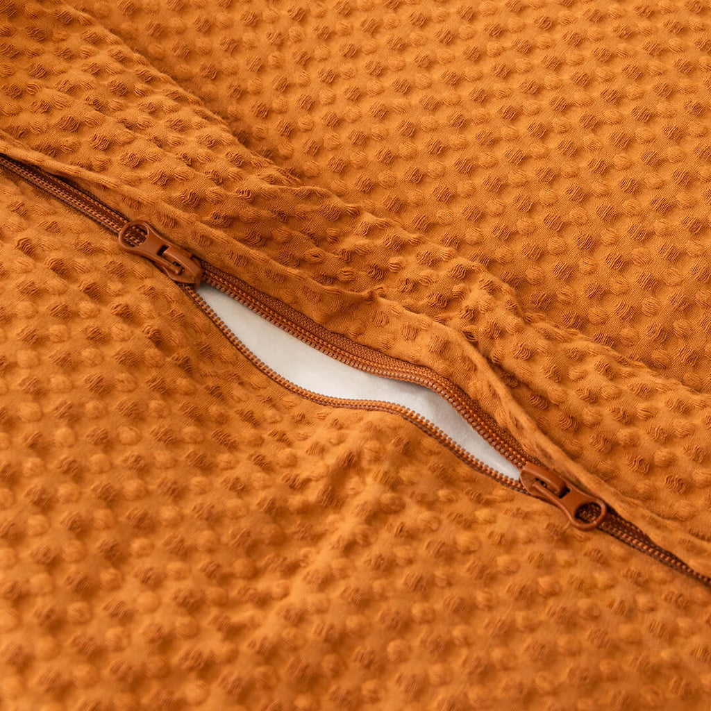 Close-up of a textured orange fabric with a zipper