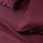 Maroon bed sheets and pillows on a bed