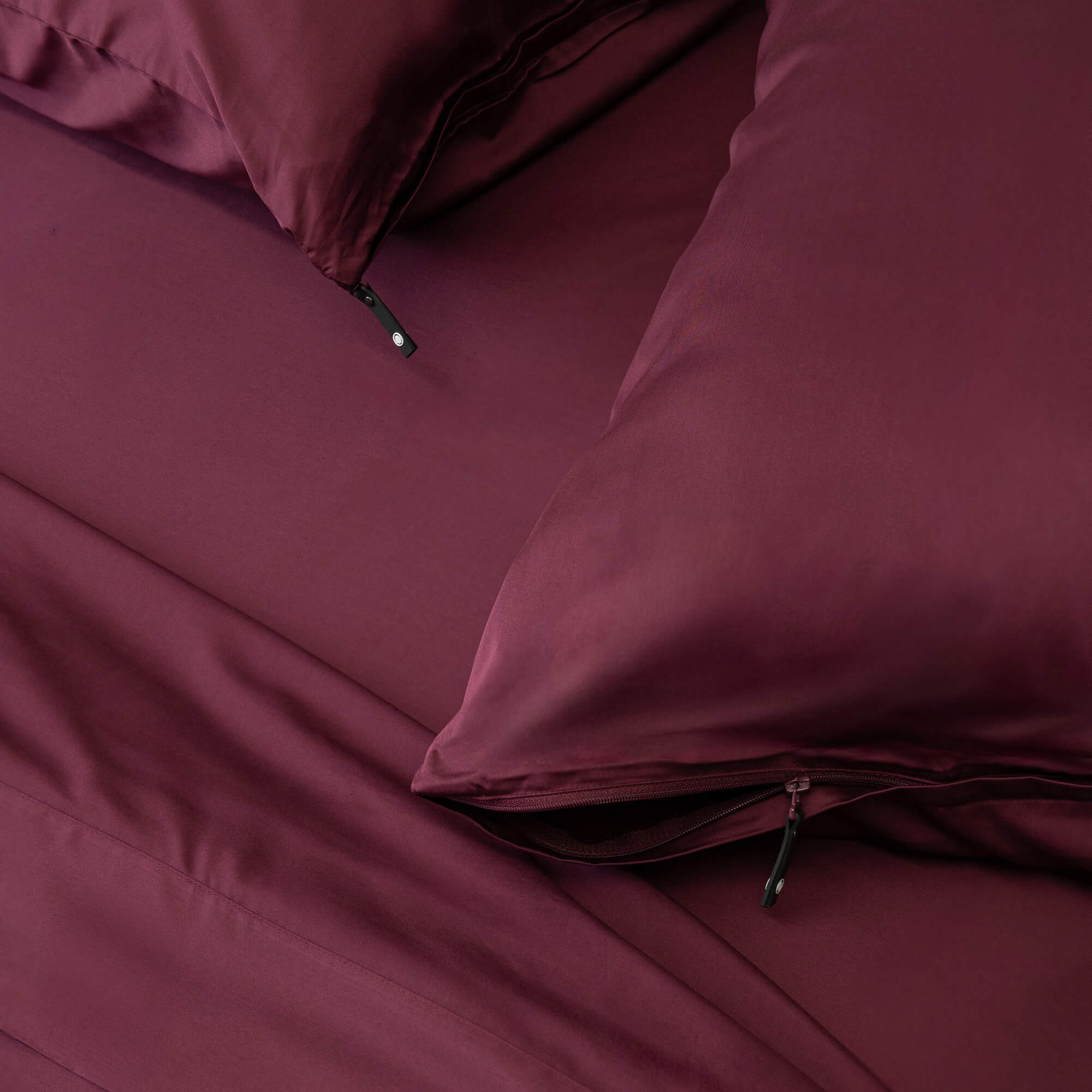 Maroon bed sheets and pillows on a bed