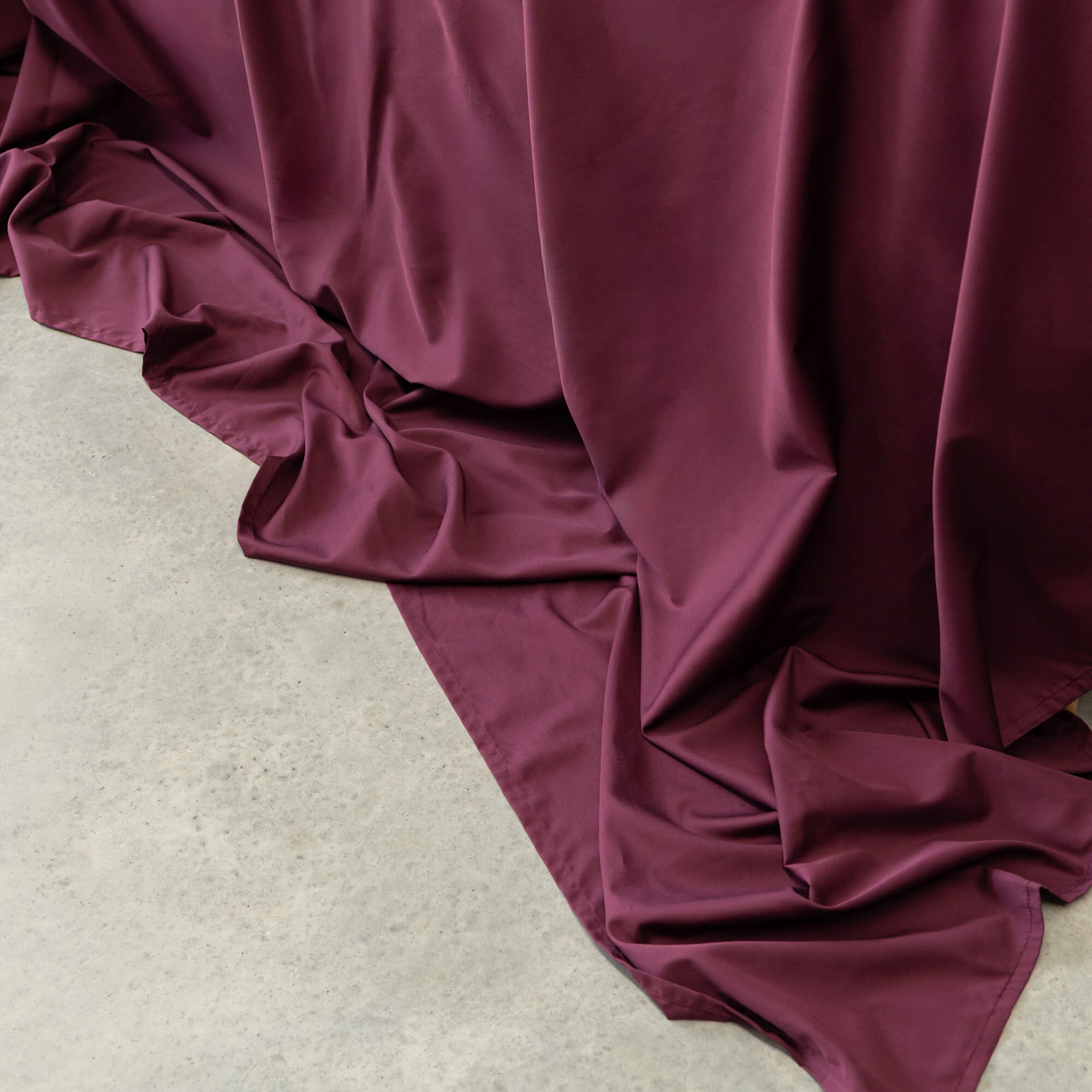 Maroon Bedding on concrete floor 