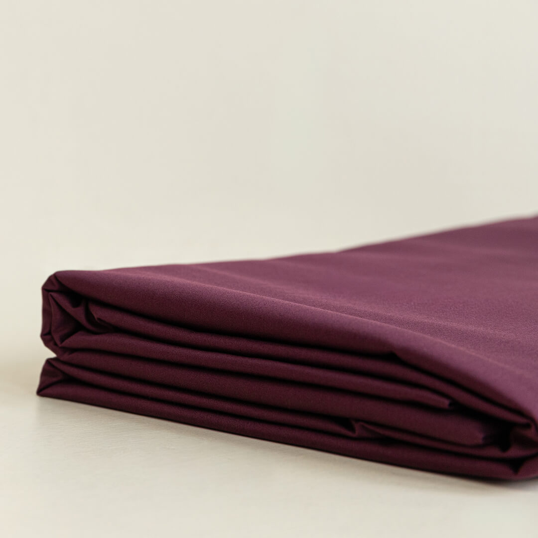 Folded burgundy fabric on a beige background.