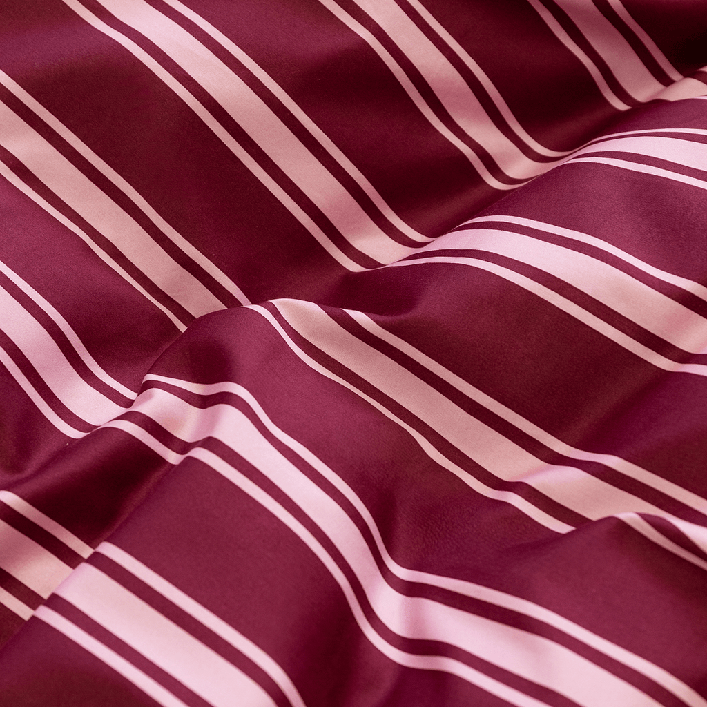 Detailed close-up of the burgundy and pale pink striped quilt cover fabric, showing its smooth texture and soft folds.