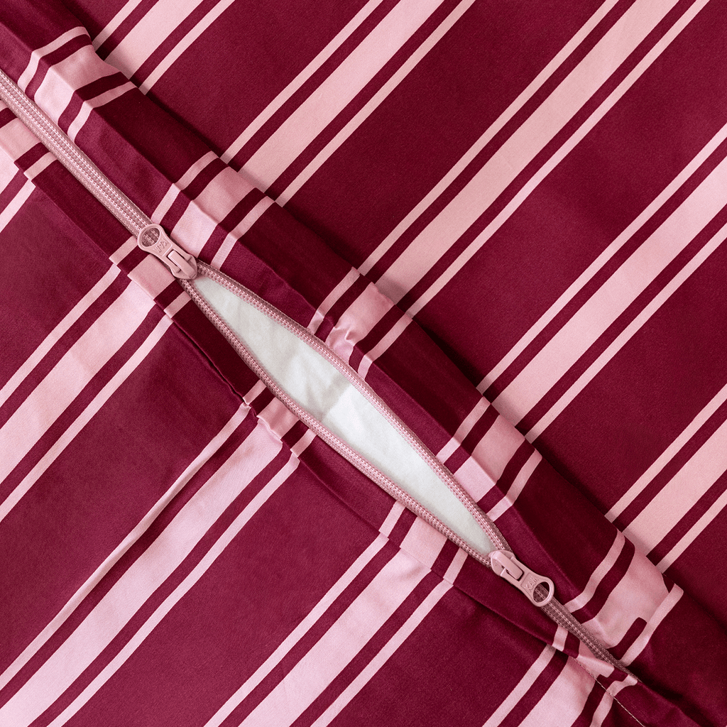 Close-up of a concealed zipper opening on a burgundy and pale pink striped quilt cover.