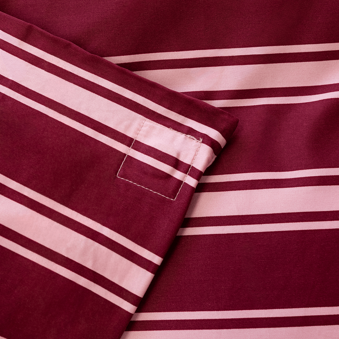 Close-up of the striped quilt cover corner, highlighting the stitched loop detail and finished seams.