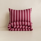 A burgundy and pale pink striped pillow displayed above a neatly folded matching quilt cover against a neutral background.