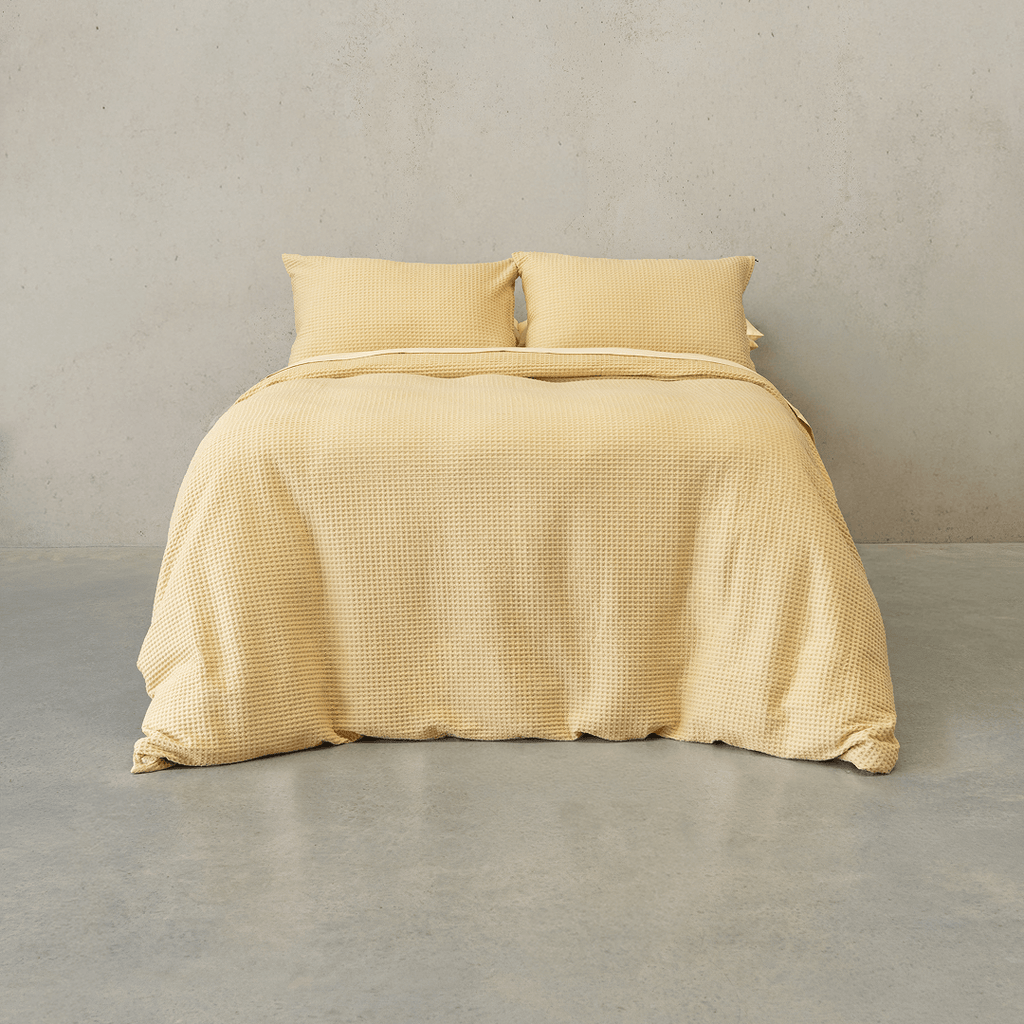Yellow waffle-weave quilt cover set made up on a double bed with two matching waffle pillowcases