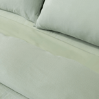 Close-up of matching sage green pillowcases and quilt cover, highlighting the soft washed fabric texture and coordinated bedding design.