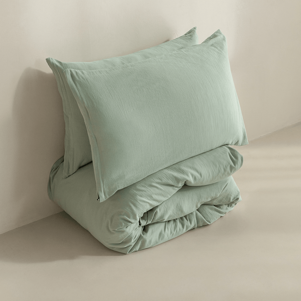 Folded sage green quilt cover set with matching pillowcases, highlighting the soft-touch fabric, casual drape, and minimalist presentation.