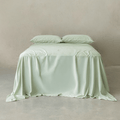 Sage green bamboo cotton sheet set styled on a bed with matching pillowcases, showcasing a smooth finish, elegant drape, and calming minimalist aesthetic.