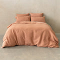 Pink textured bedspread with matching pillows on a bed against a neutral wall.