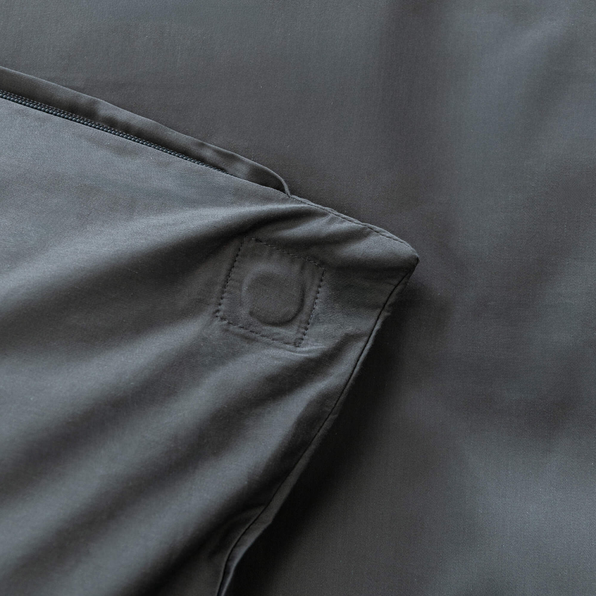 Dark grey quilt cover with magnetic button pocket against grey fabric 