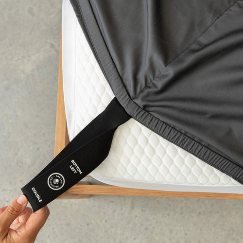Person holding a black mattress strap labeled 'Double' on a mattress.